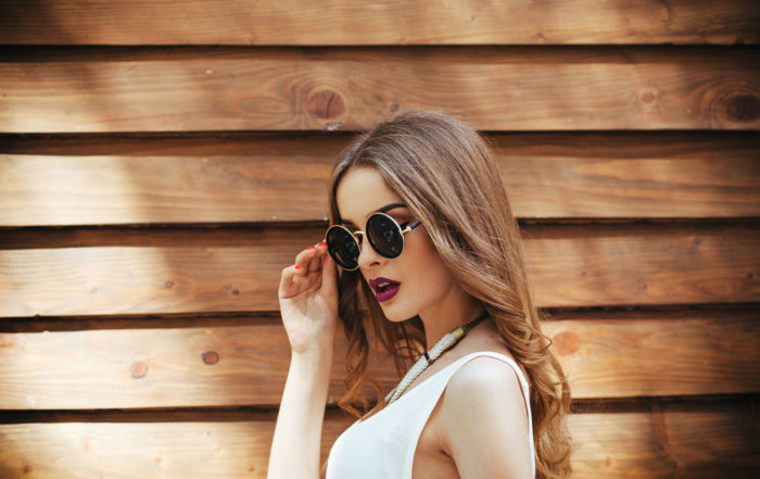 beautiful girl in sunglasses posing for the camera on brown background